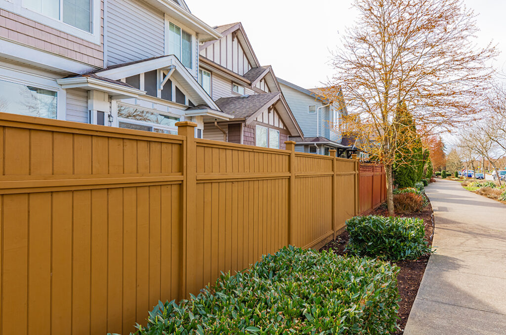 Nice wooden fence around house. Wooden fence with green lawn and trees. Street photo, nobody, selective focus